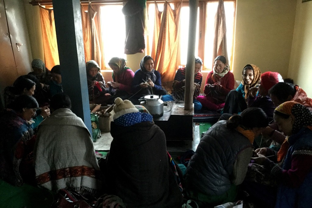 Women seated around the bukhari while making products at the NCF field station in Kibber.